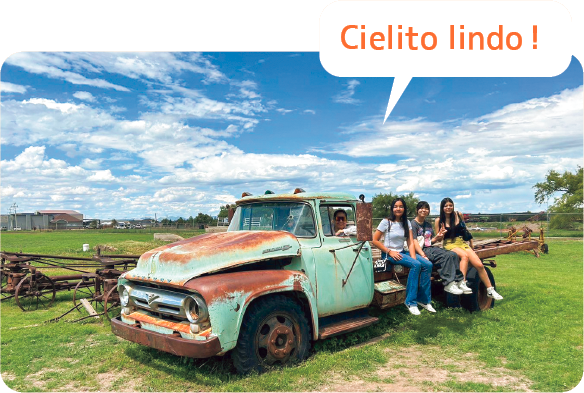 青い空と緑の大地、水色のピックアップトラックに腰かけてみんなで記念写真