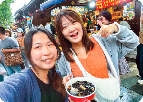 成都の街で食べ物を手に自撮りをする二人