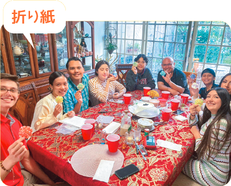 冬、大人数でテーブルを囲んで記念撮影。みんな折り紙を手に持っている