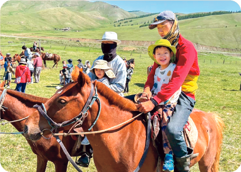 草原で馬に乗せてもらう子どもたちの写真