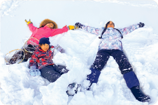 子どもも大人も新雪の上に大の字に寝転がっている写真